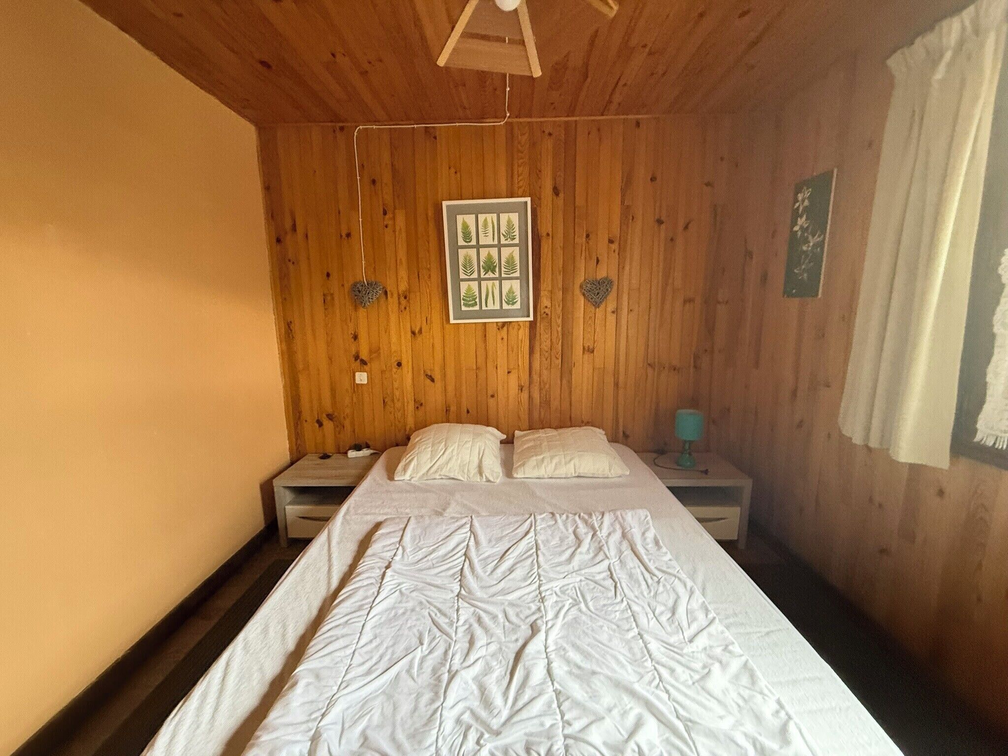 Una stanza con pannelli in legno, un letto, due comodini e un quadro incorniciato al muro.