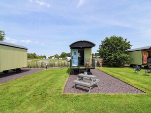 A small train station with a single platform, a bench, and a picnic table. - Quackin' Up (Whitchurch)