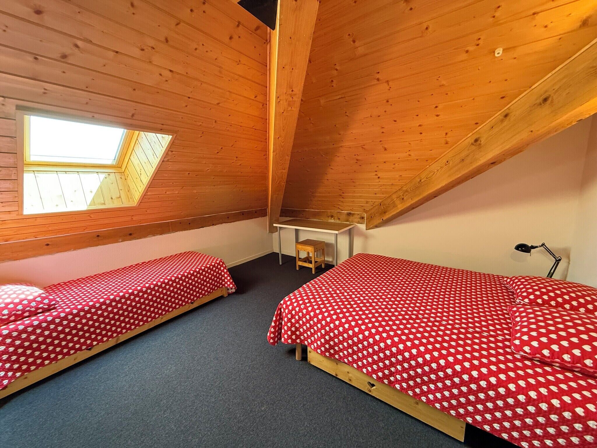 A small, cozy room with two single beds, a desk, and a skylight.