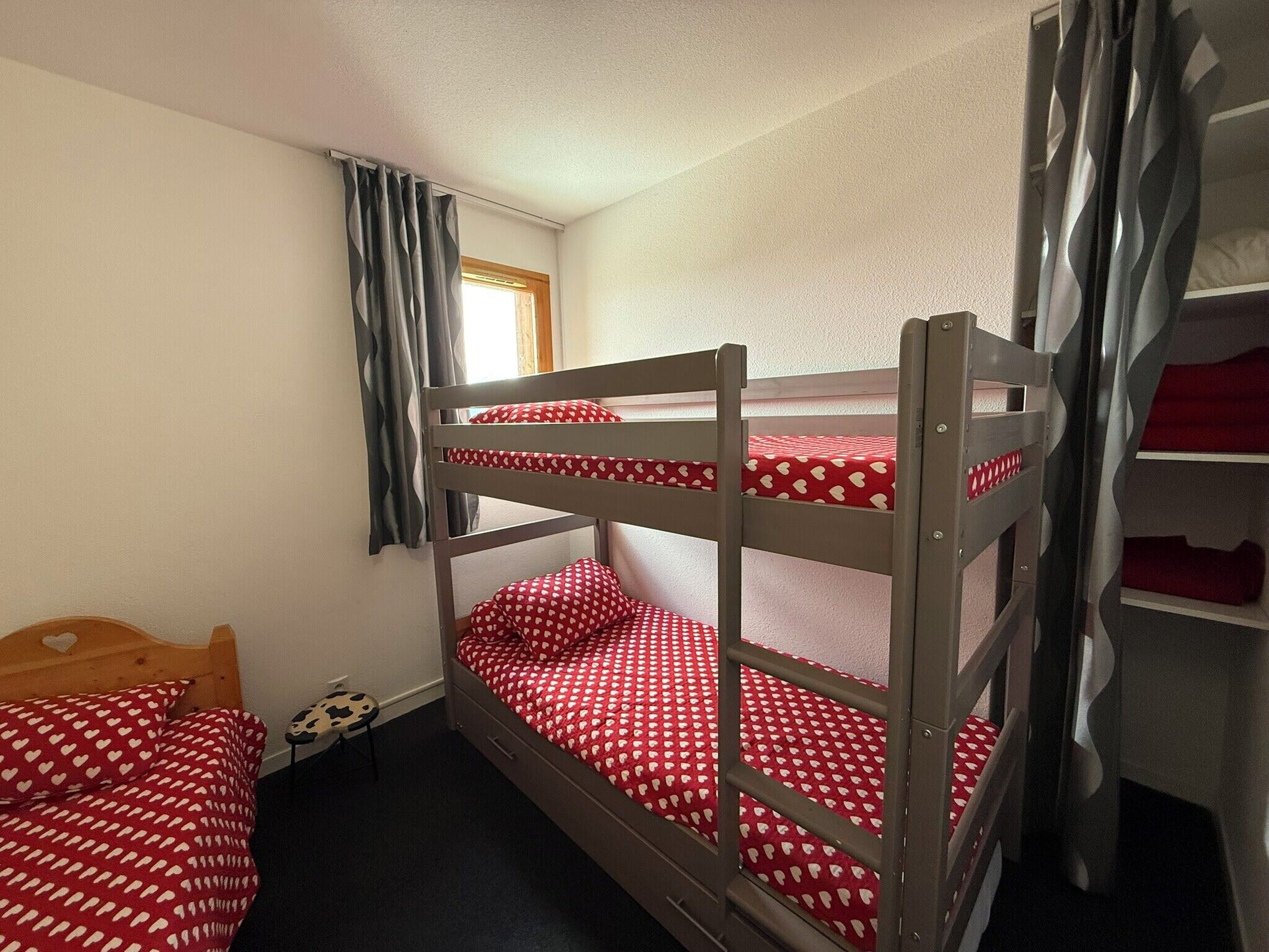 A bunk bed room with a window, a desk, and a chair.