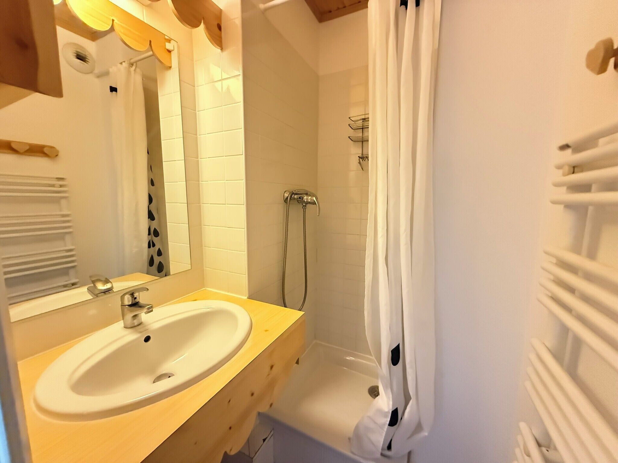 Une salle de bain équipée d’un lavabo, d’un miroir, d’une douche et d’un porte-serviettes.