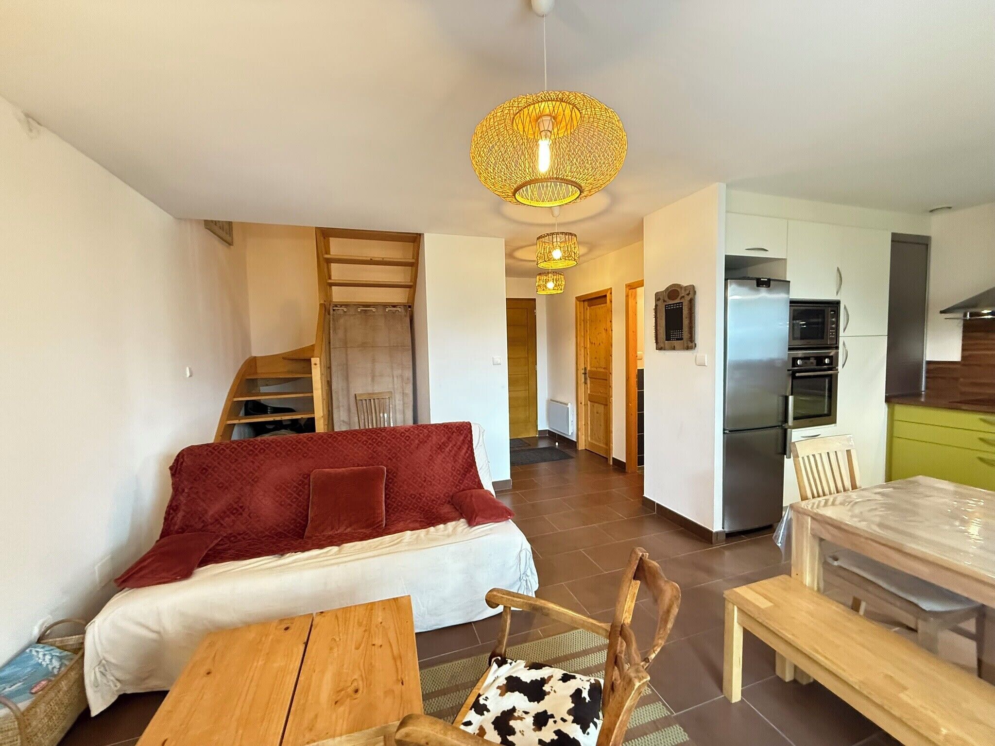A modern living room with a sofa, a dining table, and a kitchen area with a refrigerator and microwave.