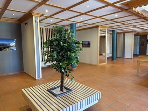 A lobby with a wooden bench, a potted plant, and a tiled floor.