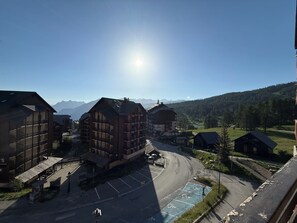 A mountain village with traditional wooden buildings, a clear sky, and a view of distant mountains.