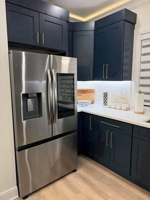 A modern kitchen with dark cabinets, stainless steel appliances, and a wooden countertop.