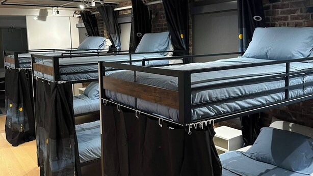 A room with bunk beds, a brick wall, and a ceiling with exposed beams. - Smith's Irish Pub & Accomodation (Vancouver)