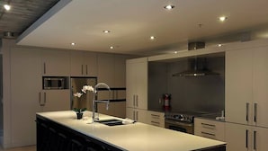 A modern kitchen with a central island, bar stools, and built-in appliances. - Smith's Irish Pub & Accomodation (Vancouver)