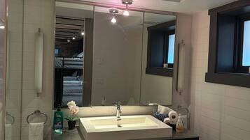 A modern bathroom with a double sink, a large mirror, and a window.