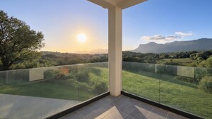 Ein Balkon mit freiem Blick auf eine grüne Landschaft und ferne Berge.