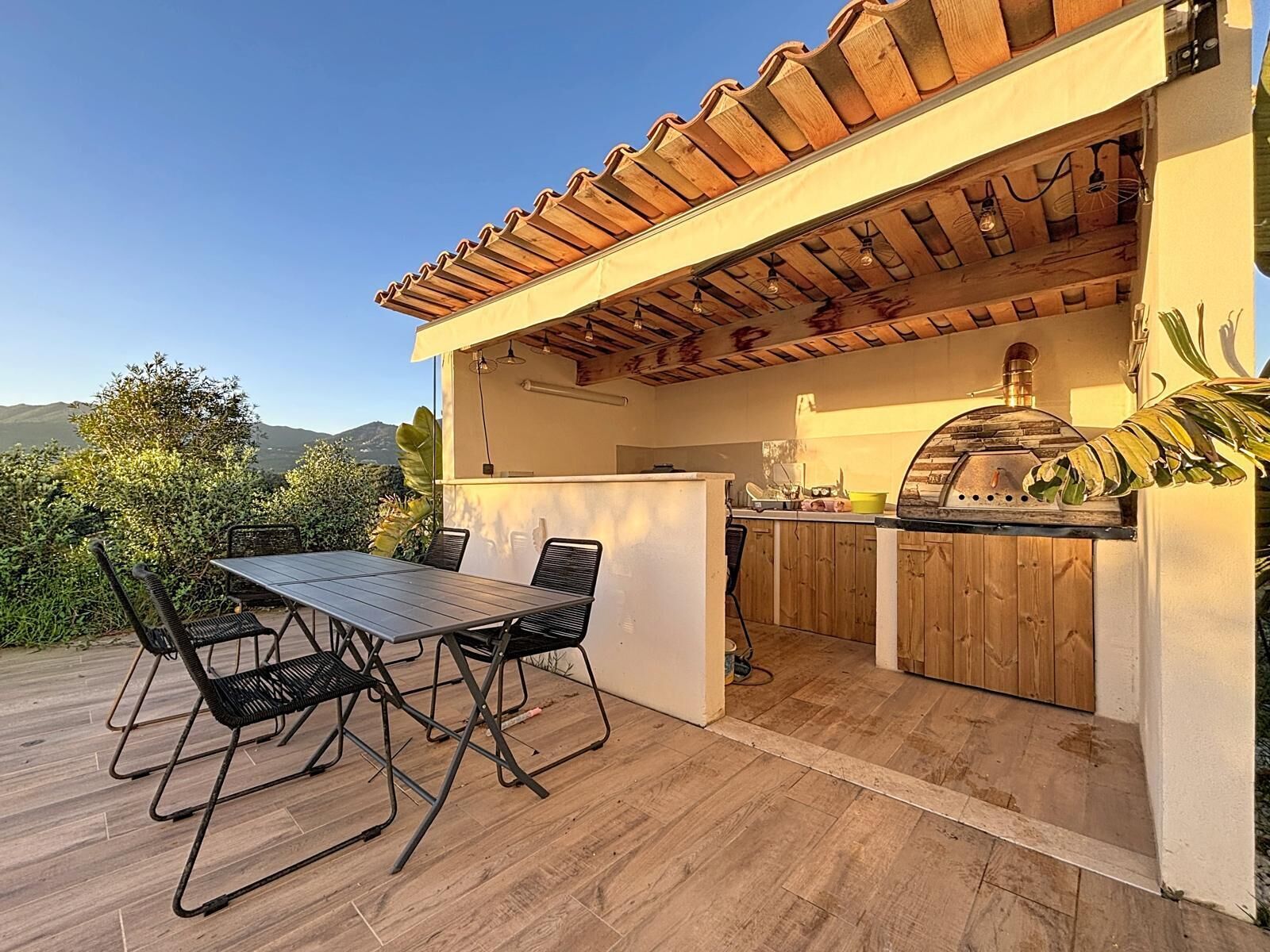Une cuisine extérieure équipée d’un barbecue, d’une table à manger et de chaises.