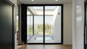 Ein modernes Interieur mit einer Glastür, die auf einen Balkon mit Blick ins Grüne führt.
