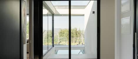 A modern interior with a glass door leading to a balcony with a view of greenery.