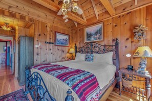 Ein Schlafzimmer einer Holzhütte mit einem Bett, einem Nachttisch, einer Lampe und einer Wanduhr.
