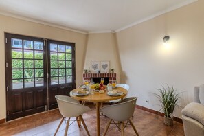 A dining area with a round table, chairs, a fireplace, and a view through a glass door. - #389 Villa with shared pool | Spacious 3-bedroom (Albufeira)