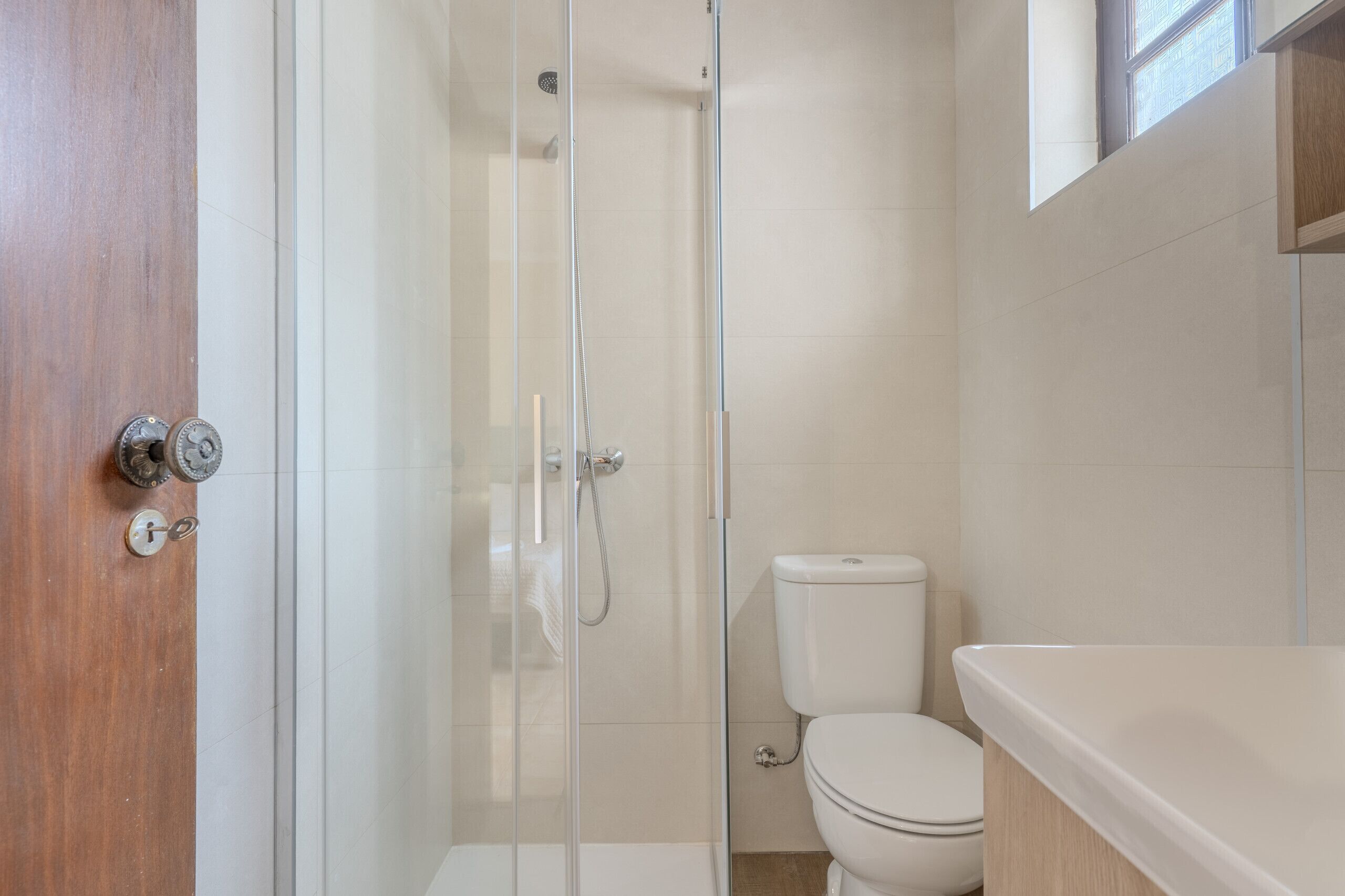 Un baño con cabina de ducha de vidrio, un inodoro y una puerta de madera.
