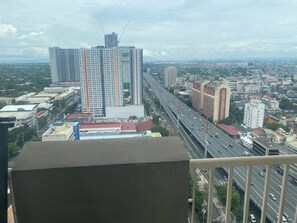 A high-rise building with multiple floors and a construction crane, surrounded by a cityscape with roads and other buildings. - Cozy 1-bedroom 40sqm twin condo unit with AC in delightful Makati City. (Makati City)