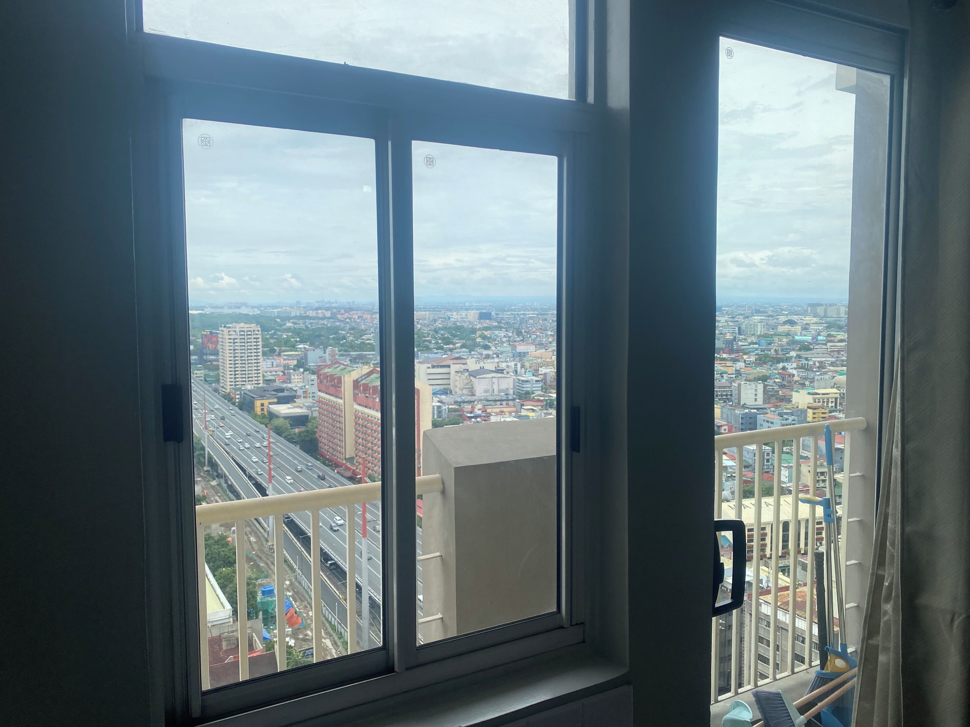 Una finestra con vista su un paesaggio urbano, che include edifici e un'autostrada.