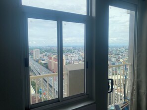 A window with a view of a cityscape, including buildings and a highway. - Cozy 1-bedroom 40sqm twin condo unit with AC in delightful Makati City. (Makati City)