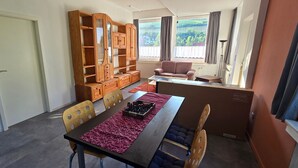 Een eetgedeelte met een tafel, stoelen, een houten kast en een bank.