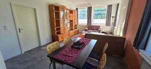 A dining area with a table, chairs, a wooden cabinet, and a sofa. - Apartment 'FeWo Meyer in Hüddingen' with Private Garden and Wi-Fi (Bad Wildungen)