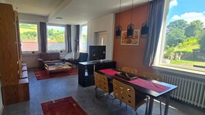 Een moderne woonkamer met een bank, een salontafel, een televisie en een eethoek met stoelen en een tafel.