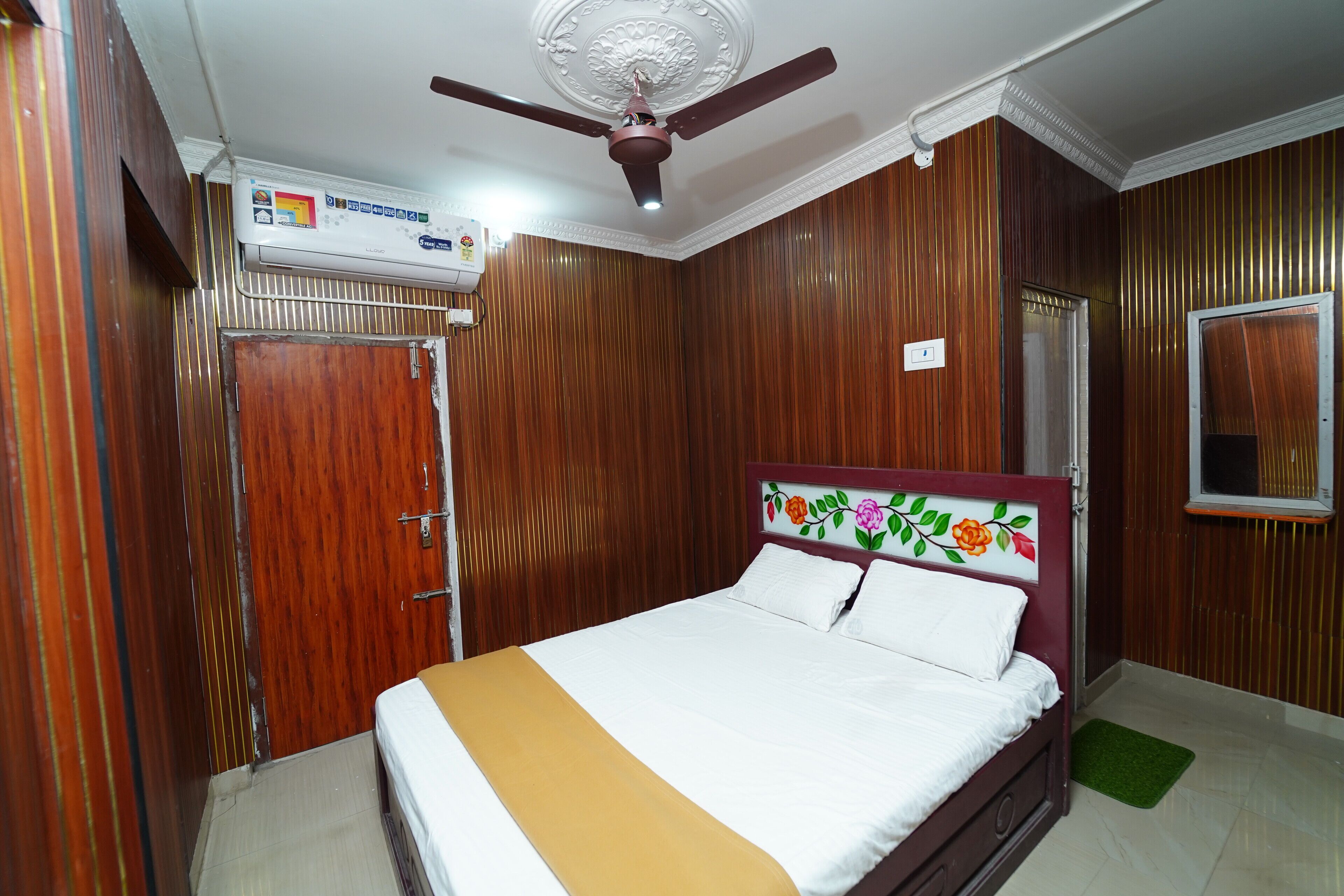 Quarto com cama, ventilador de teto, ar condicionado e painéis de madeira.