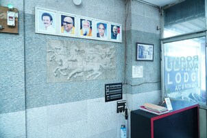 Una recepción con fotografías enmarcadas, un relieve de piedra y un letrero que dice 'Poonam Lodge A/C & Non A/C'.