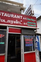 Un edificio con un letrero de restaurante y un letrero de Udhaya Lodge que ofrece habitaciones y estacionamiento.