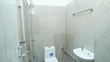 Un baño pequeño con inodoro, lavamanos, ducha y un balde verde.