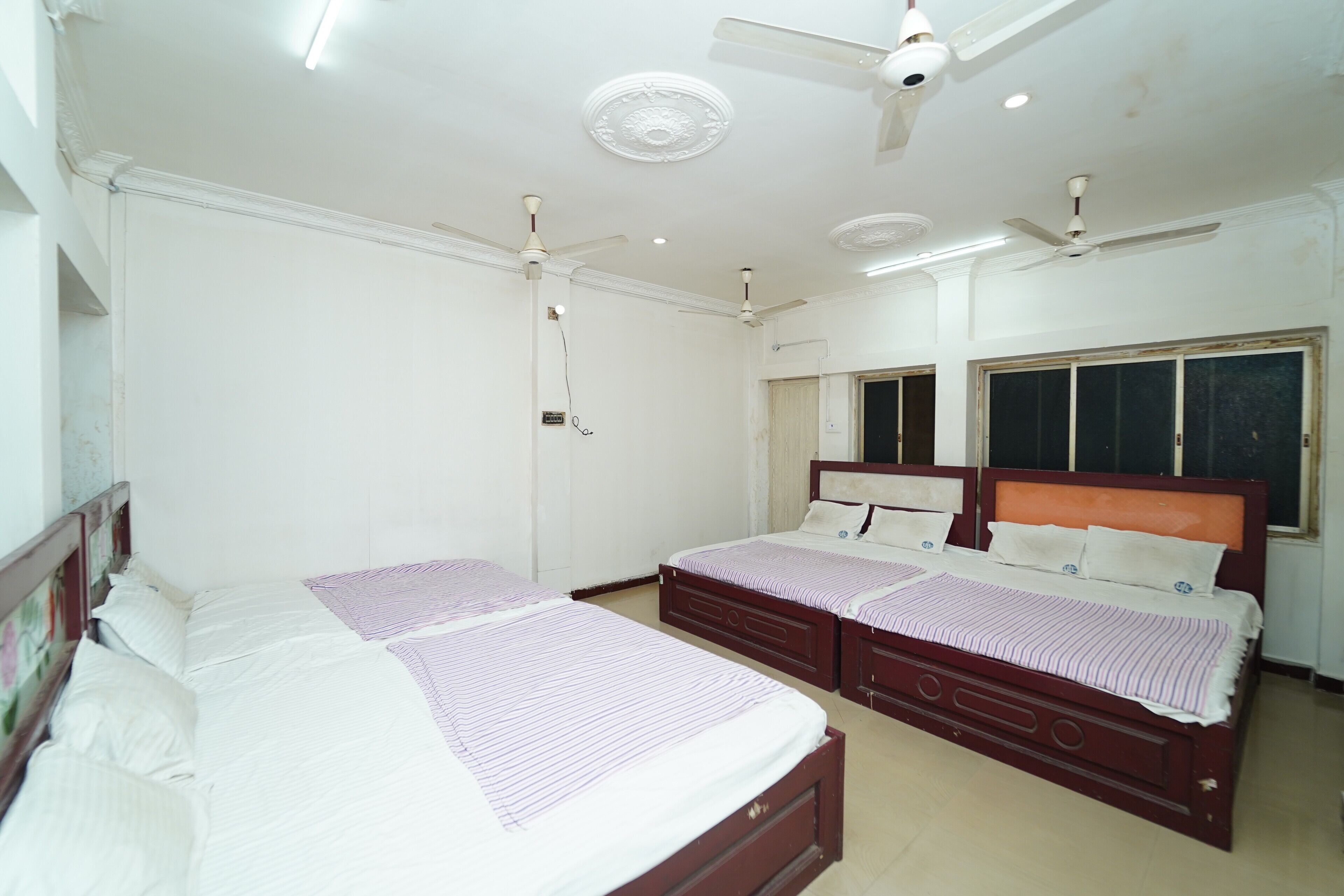 A bedroom with two beds, a ceiling fan, and a window with a view.