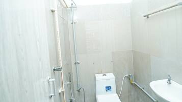 Un baño pequeño con inodoro, lavamanos y ducha.