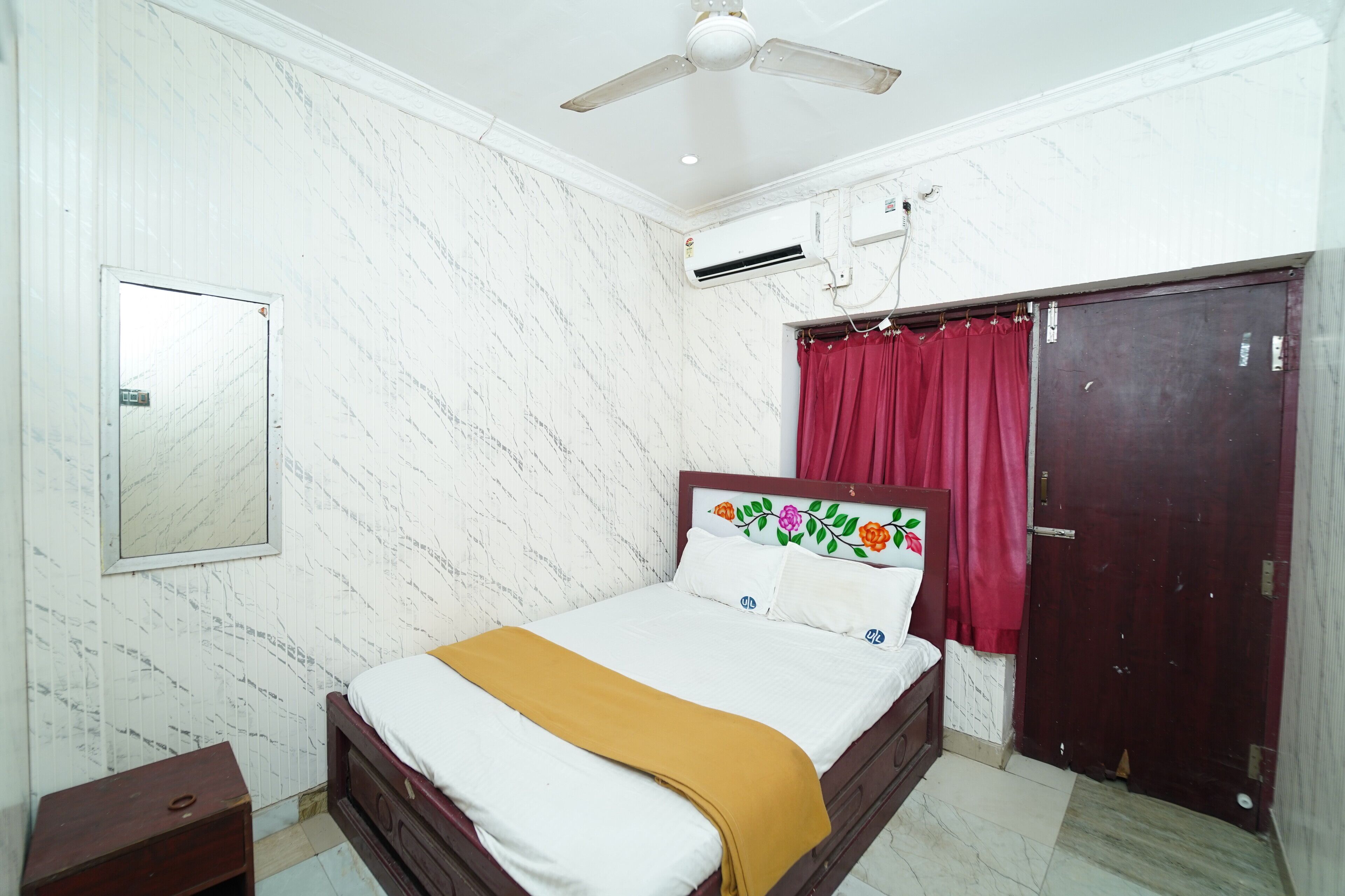 Quarto com cama, ventilador de teto, ar condicionado, guarda-roupa e espelho.