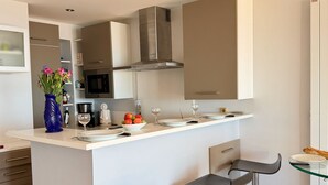 A modern kitchen with a central island, bar stools, and a microwave. - Le Rivage à Pornichet (Pornichet)