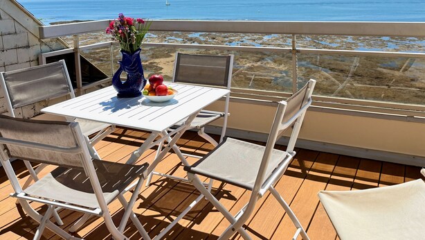 A balcony with a table, chairs, and a vase of flowers. - Le Rivage à Pornichet (Pornichet)