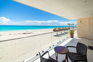Ein Balkon mit Blick auf einen Strand, einem Tisch und Stühlen.
