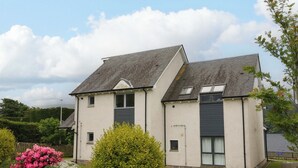 A two-story residential building with a symmetrical facade, a pitched roof, and a small front garden with flowering shrubs. - Craigard (Aberfeldy)