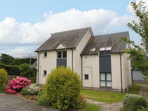 A two-story residential building with a symmetrical facade, a pitched roof, and a small front garden with flowering shrubs. - Craigard (Aberfeldy)