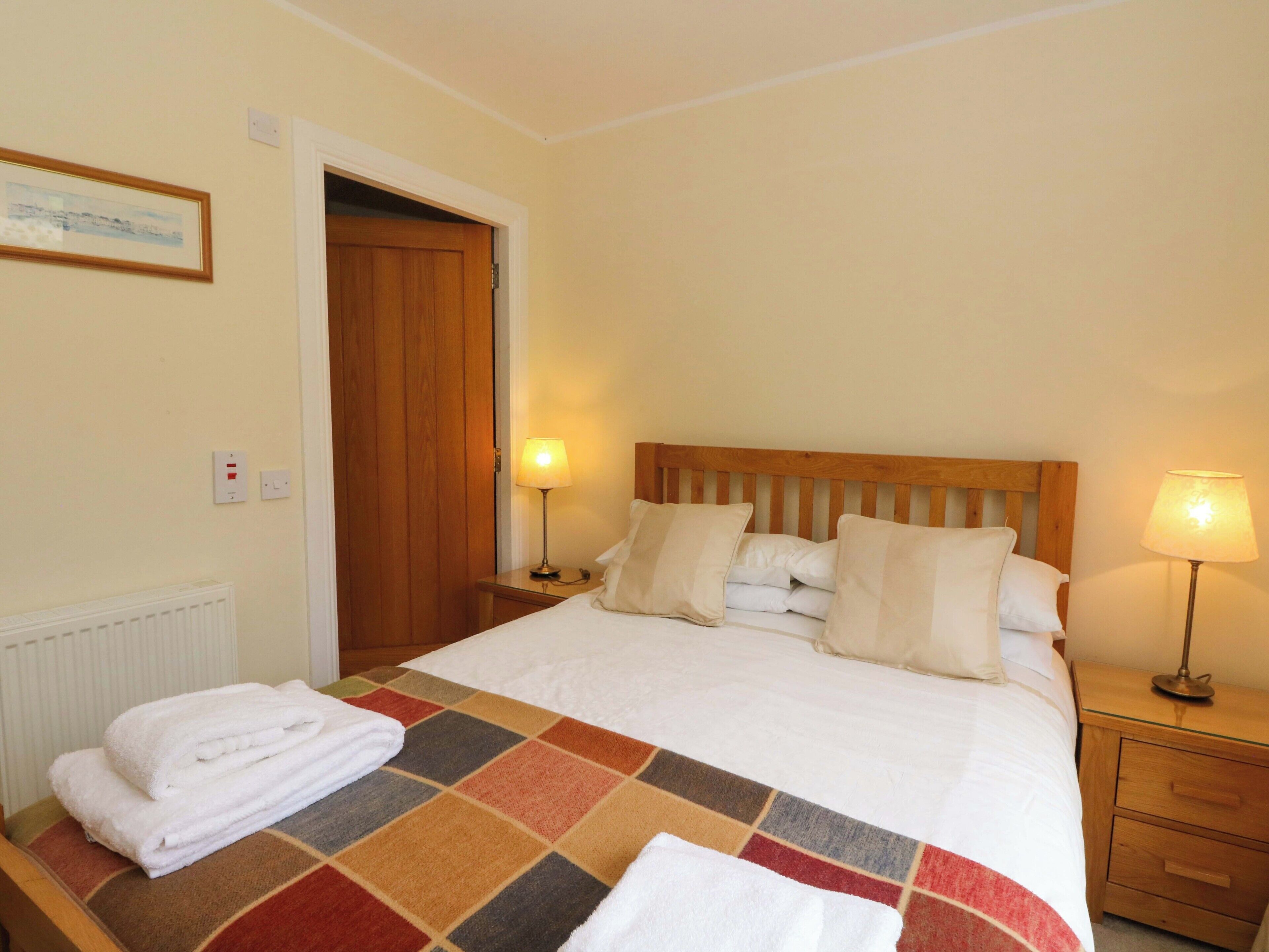 A hotel room with a bed, two bedside tables, a wooden door, and a radiator.