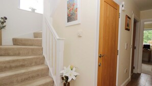A staircase with carpeted steps, a wooden door, and a wall-mounted light switch. - Craigard (Aberfeldy)