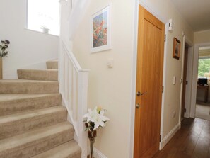 A staircase with carpeted steps, a wooden door, and a wall-mounted light switch. - Craigard (Aberfeldy)