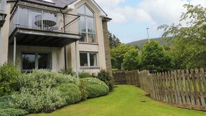 A two-story house with a balcony and a fenced yard. - Craigard (Aberfeldy)