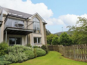 A two-story house with a balcony and a fenced yard. - Craigard (Aberfeldy)