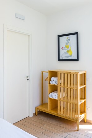 A room with a wooden cabinet with towels, a white door, and a framed picture on the wall. - Viewsuvio Two Apartments & Terraces (Naples)