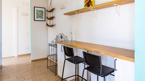 A room with a wooden floor, a white door, a wall-mounted shelf with a picture, two black chairs, and a table. - Viewsuvio Two Apartments & Terraces (Naples)