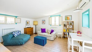 A room with a sofa, a dining table, a lamp, a radiator, and a bookshelf. - Viewsuvio Two Apartments & Terraces (Naples)