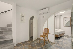 Habitació amb un llit, una cadira, una escala i una porta d'arc.