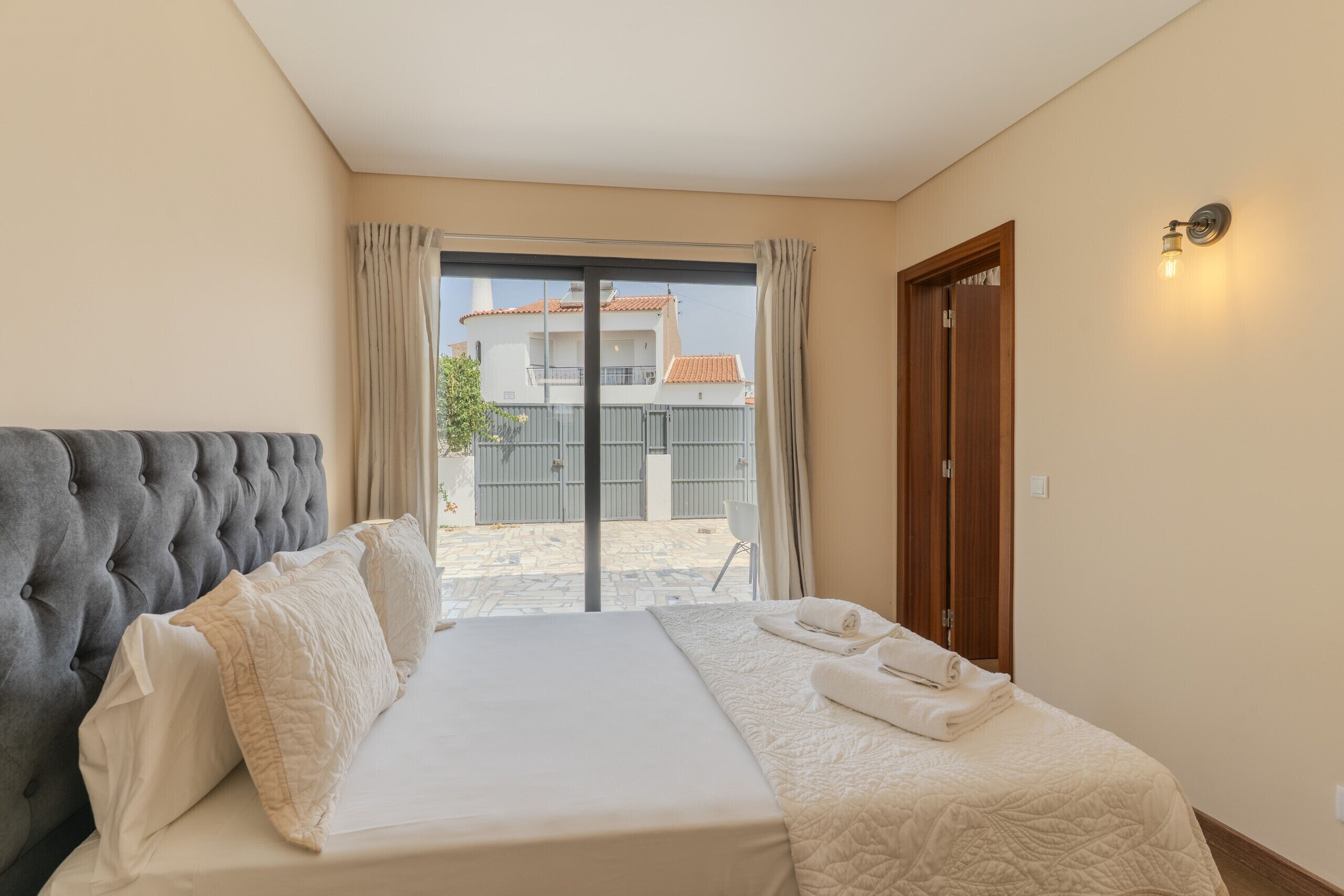 Een hotelkamer met een bed, een houten deur en uitzicht op buiten.