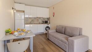 A compact living space with a kitchenette, a dining area with breakfast items, and a sofa. - #390 New Town Apartment with Shared Pool (Albufeira)