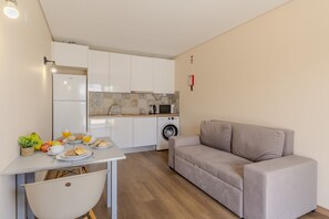 Ein kompakter Wohnbereich mit Küchenzeile, einem Essbereich mit Frühstücksangeboten und einer Couch.