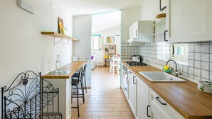 Et moderne køkken med træbordplader, en vask og et spiseområde med stole og et bord.